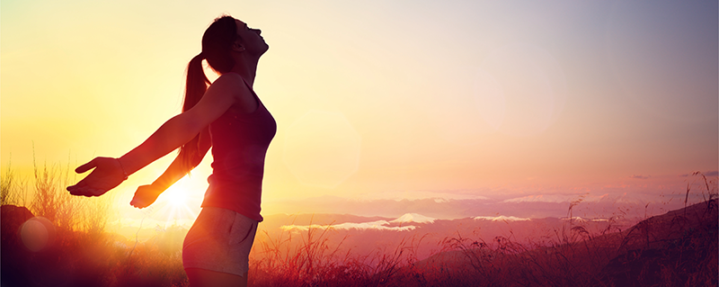 WELLNESS girl standing in front of the sunset