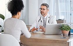 Woman sitting with her back to the camera facing a doctor across a desk