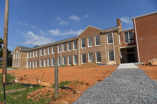 Dandridge School Lofts A large brick school building stands on a cleared lot with a gravel walkway in front.