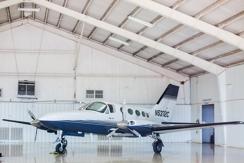 A small propeller airplane is parked inside a spacious airport hangar.