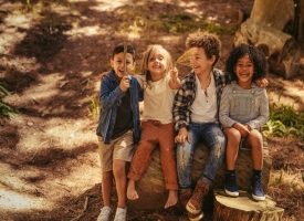 smiling children sitting on log outdoors