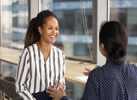 Two young female colleagues lead talk met in office A young therapist is smiling in conversation with a supervisor