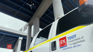 Drone flying under a highway overpass near a Tennessee Department of Transportation (TDOT) truck marked for official use.
