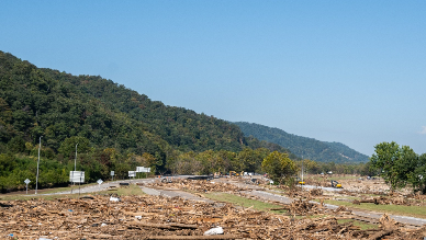 Drone flying over a flood-impacted area with debris and muddy terrain, used for disaster assessment and response.