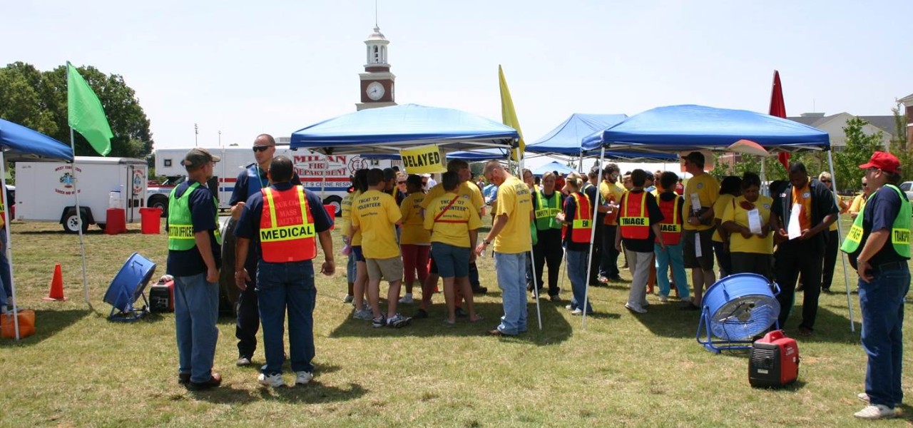 People in an exercise staging area People participating in a large exercise outside under several pop-up canopy tents