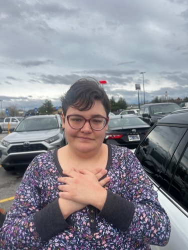 Kayln smiles with her hands clasped over her chest.