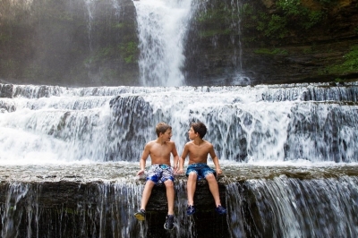 boys sitting on edge of waterfall boys sitting on edge of waterfall