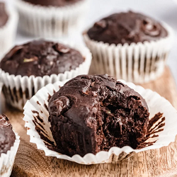 Several chocolate muffins, the one in the foreground has a bite taken out of it.