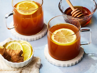 two cups of turmeric ginger tea with lemon on top