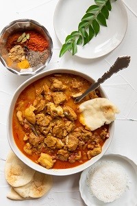Mama Menachery's Chicken Curry a bowl of chicken curry with naan on the side