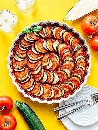 Ratatouille Ratatouille in a dish with whole tomatoes and zucchini scattered around the counter