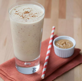 smoothie on a napkin with a paper straw and a little dish of peanut butter next to it