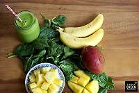 Beginner's Luck Green Smoothie ingredients for the beginner's luck green smoothie on a table with a green smoothie in a glass