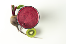 Purple Power Smoothie in a glass with a beet and kiwi on the counter Purple Power Smoothie in a glass with a beet and kiwi on the counter