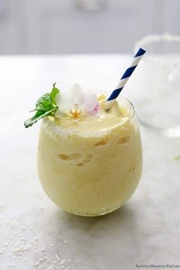 Virgin Piña Colada non-alcoholic pina colada in a glass with a blue and white paper straw; garnished with a tropical flower