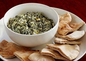 creamy spinach feta dip with pita chips around it