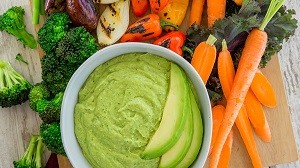 avocado pesto dip with assorted veggies around it