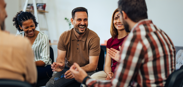 A group of five employees sitting in a circle laughing and talking