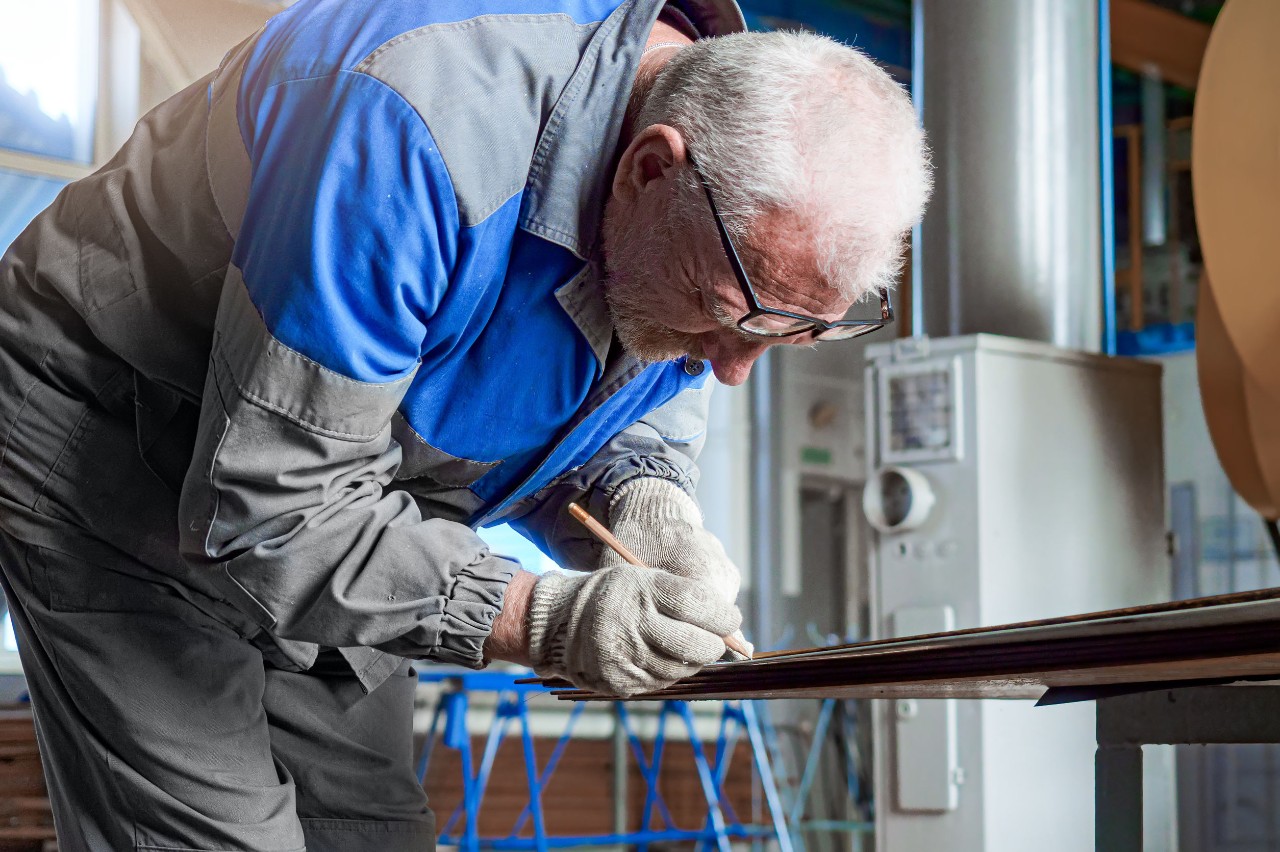 Elderly Employees Older man holding a pencil bent over doing work