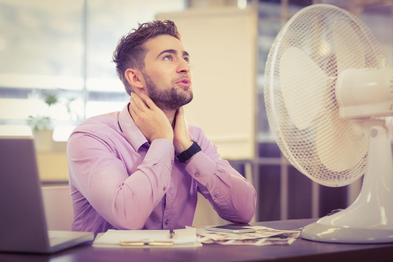 No Air Conditioning Man sits in front of an electric fan