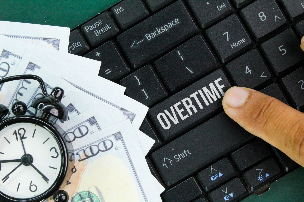 Keyboard with a button that says Overtime next to a watch and cash Overtime Pay