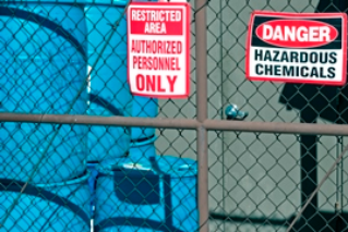 Hazardous Duty Pay Fence with signs that say Restricted Area: Authorized Personnel Only and Danger: Hazardous Chemicals