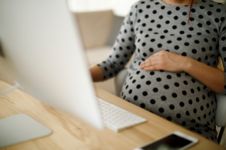 Pregnant Employees Pregnant woman sitting in front of a computer at a desk