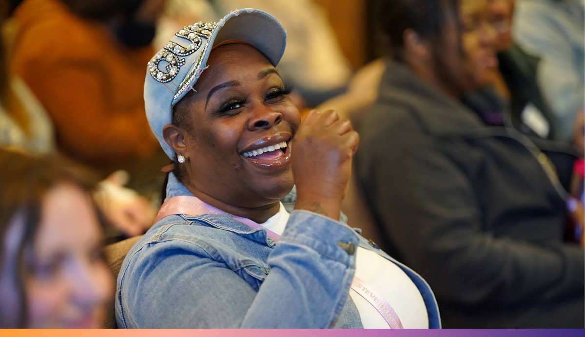 UpRise Nashville A woman wearing a ballcap smiles while sitting among other people in a room