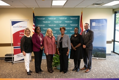 Five women and a man pose for a photo in front of a backdrop of Nashville State Community College